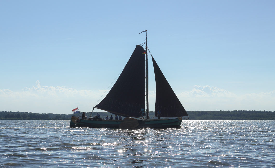 Seitliche Ansicht auf die Twee Gebroeders auf dem Wasser mit gegenlicht, das Schiff sieht dadurch Silhouettenartig aus.